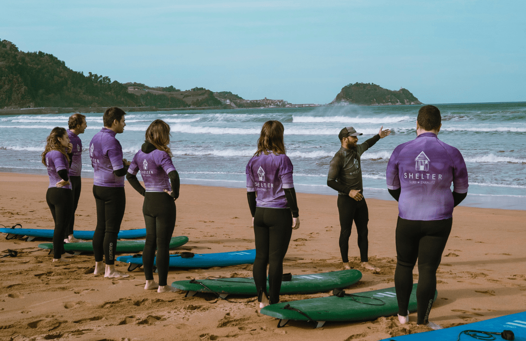 Instructores de Shelter Surf dando una clase de surf con Lueira en la playa de Zarautz